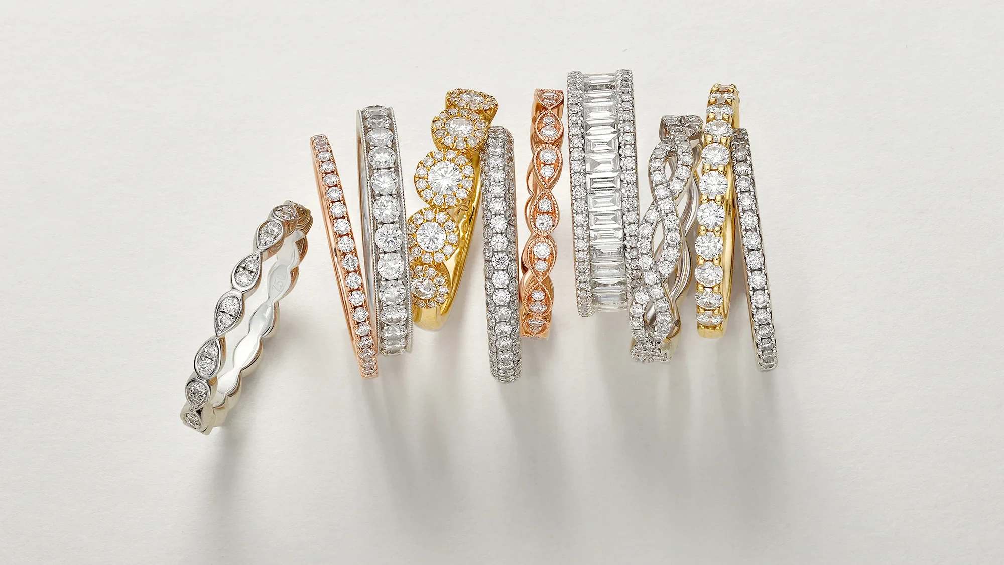 Diamond rings and bands arranged on a softly lit neutral surface