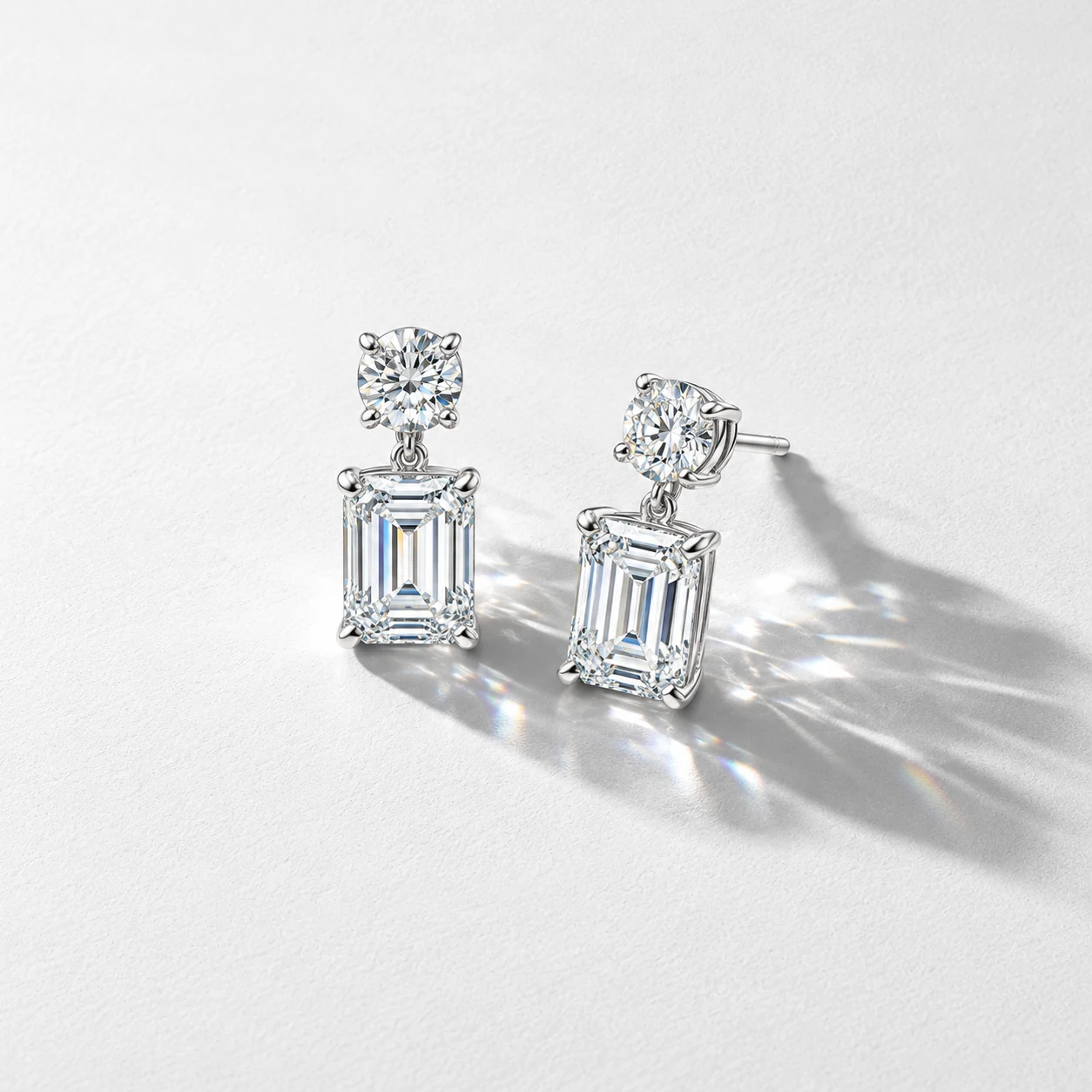 A pair of rectangular-stone drop earrings arranged on a white textured background
