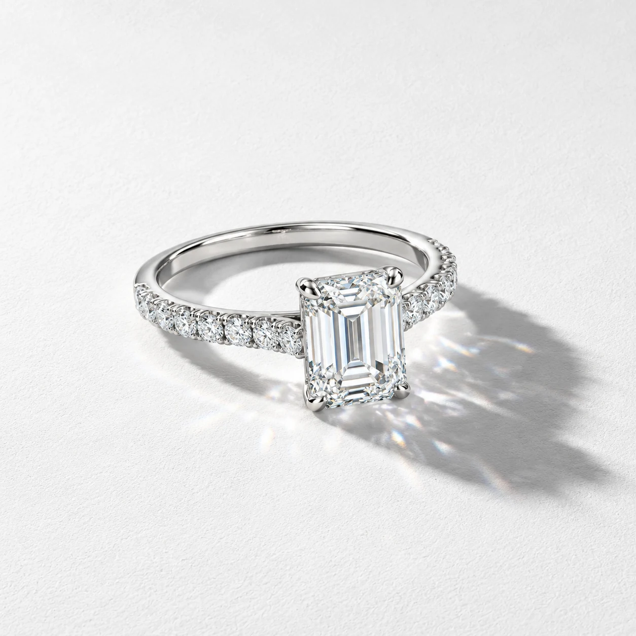 A rectangular-stone ring with a delicate stone-set band on a white textured background